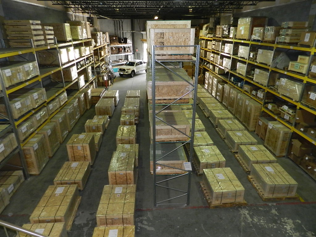 Full warehouse overview — racking shelves stocked with locomotive parts and crates